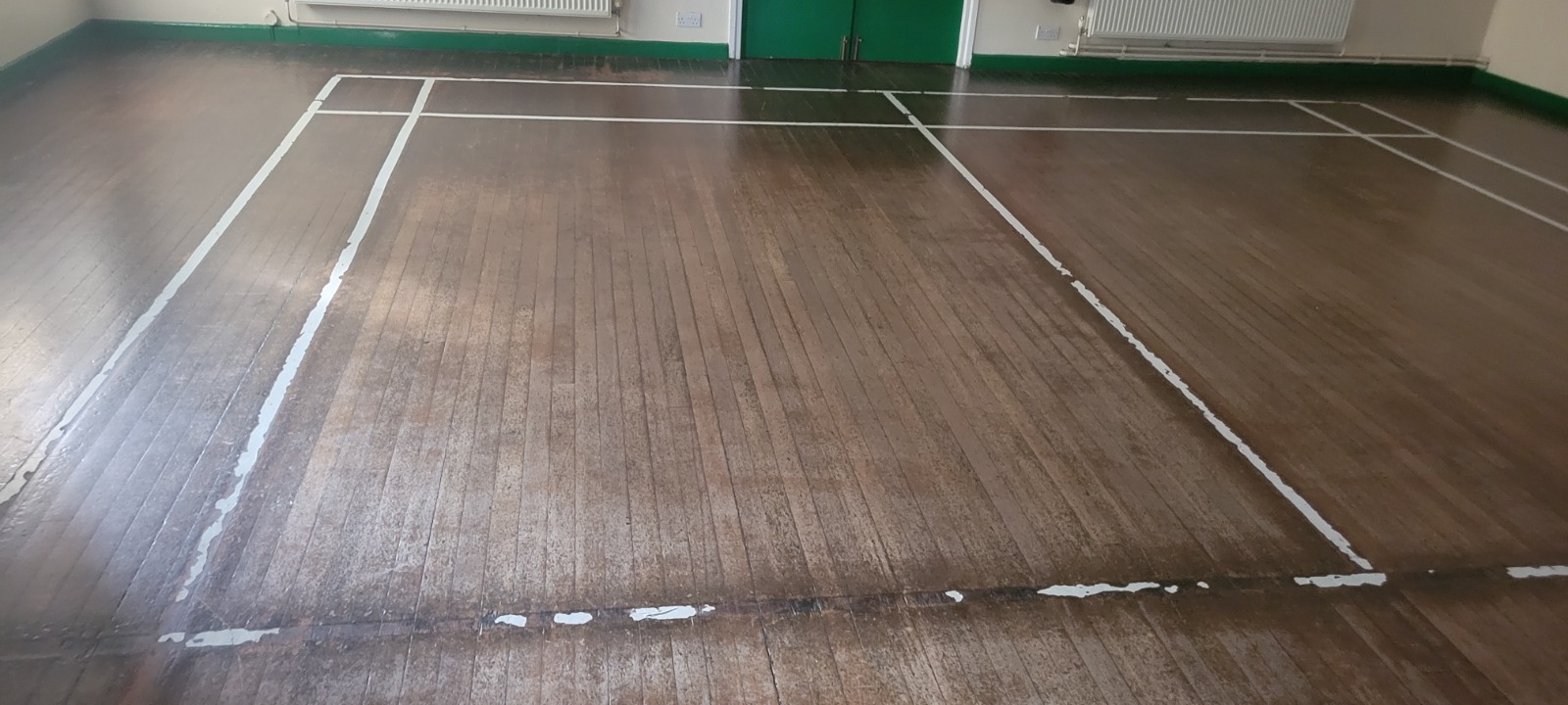 Worn maple strip sports hall floor in Tottenham awaiting Commercial Floor Sanding, showing faded court lines and dull timber surface.