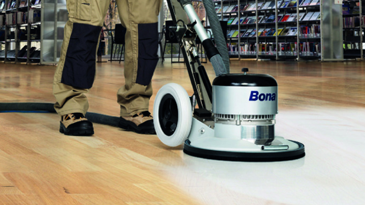 Commercial Floor Sanding in Tottenham on an oak hardwood strip floor, technician using a Bona dust-controlled sanding machine in a busy commercial space.