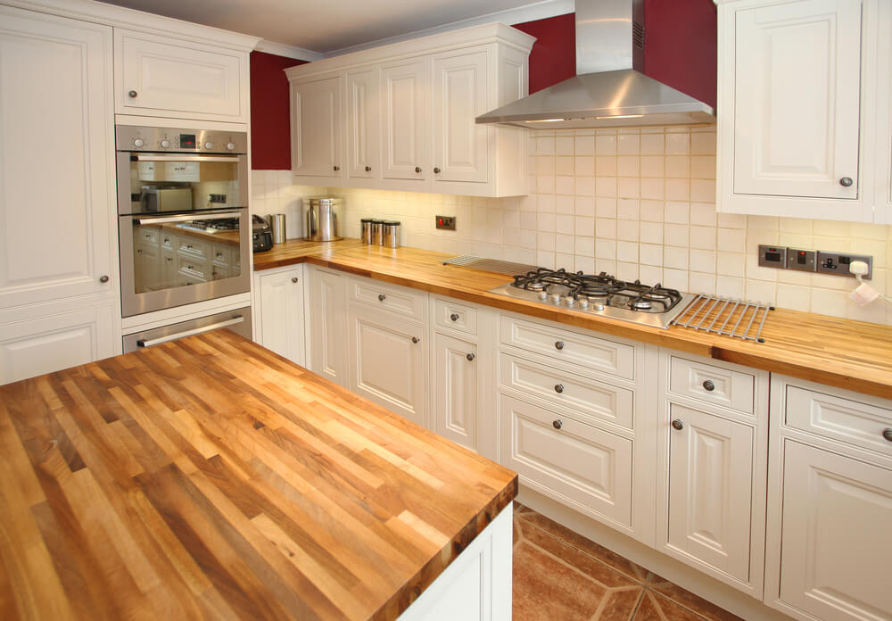 Worktop Refinishing in Tottenham showing restored oak butcher-block kitchen worktops with a ceramic tile kitchen floor in a bright white shaker-style kitchen
