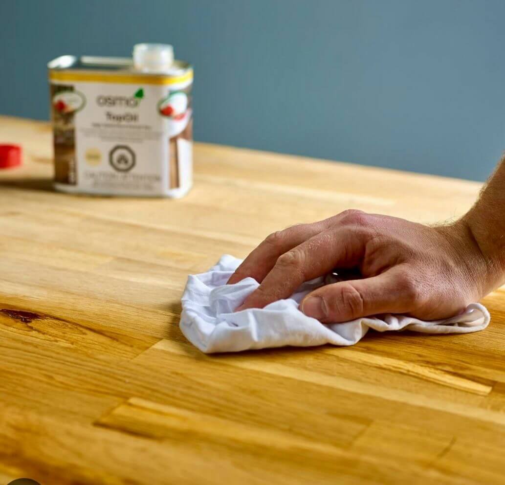 Worktop Refinishing in Tottenham with oil being applied by hand to a solid oak butcher-block kitchen worktop beside a light oak wooden floor