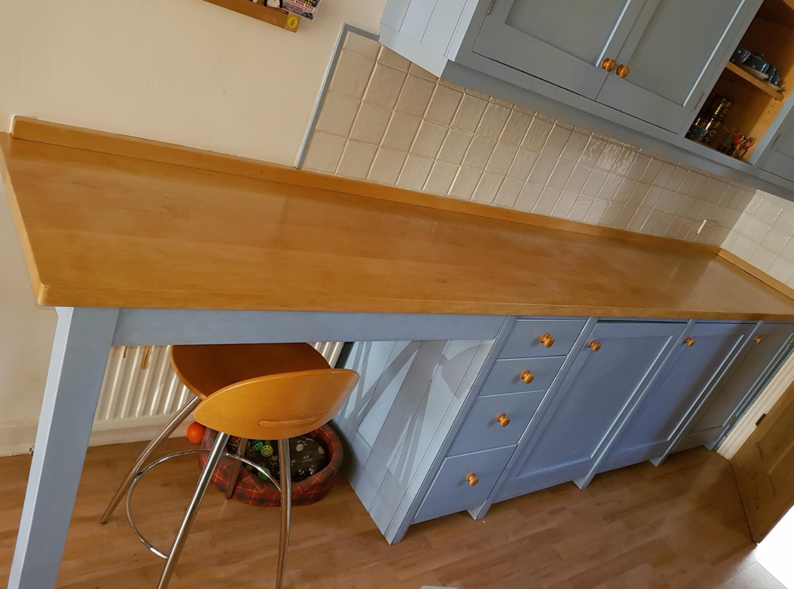 Worktop Refinishing in Tottenham on a long solid wood kitchen counter above an oak-effect laminate floor with blue painted cabinets